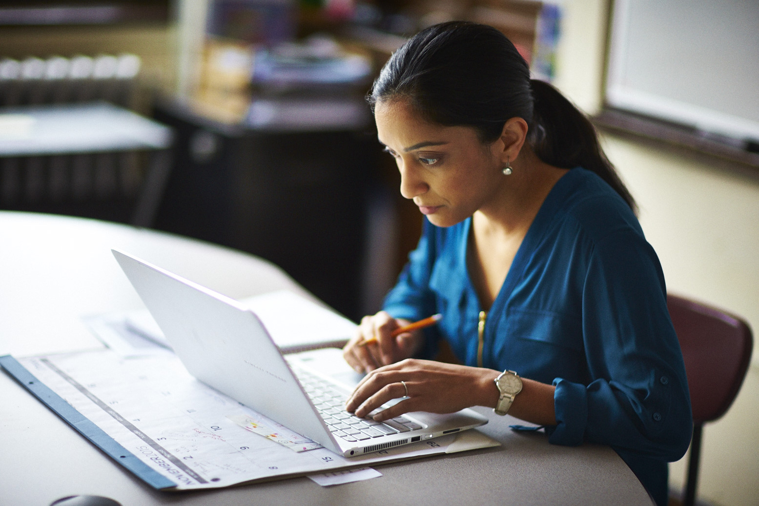A teacher planning for a year of math learning with Eureka Math Squared at her desk on a computer with a calendar. 